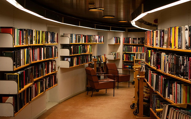 A hallway in a library lined with shelves of books.